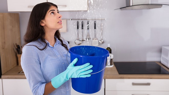 young_woman_holding_bucket_leaking_roof